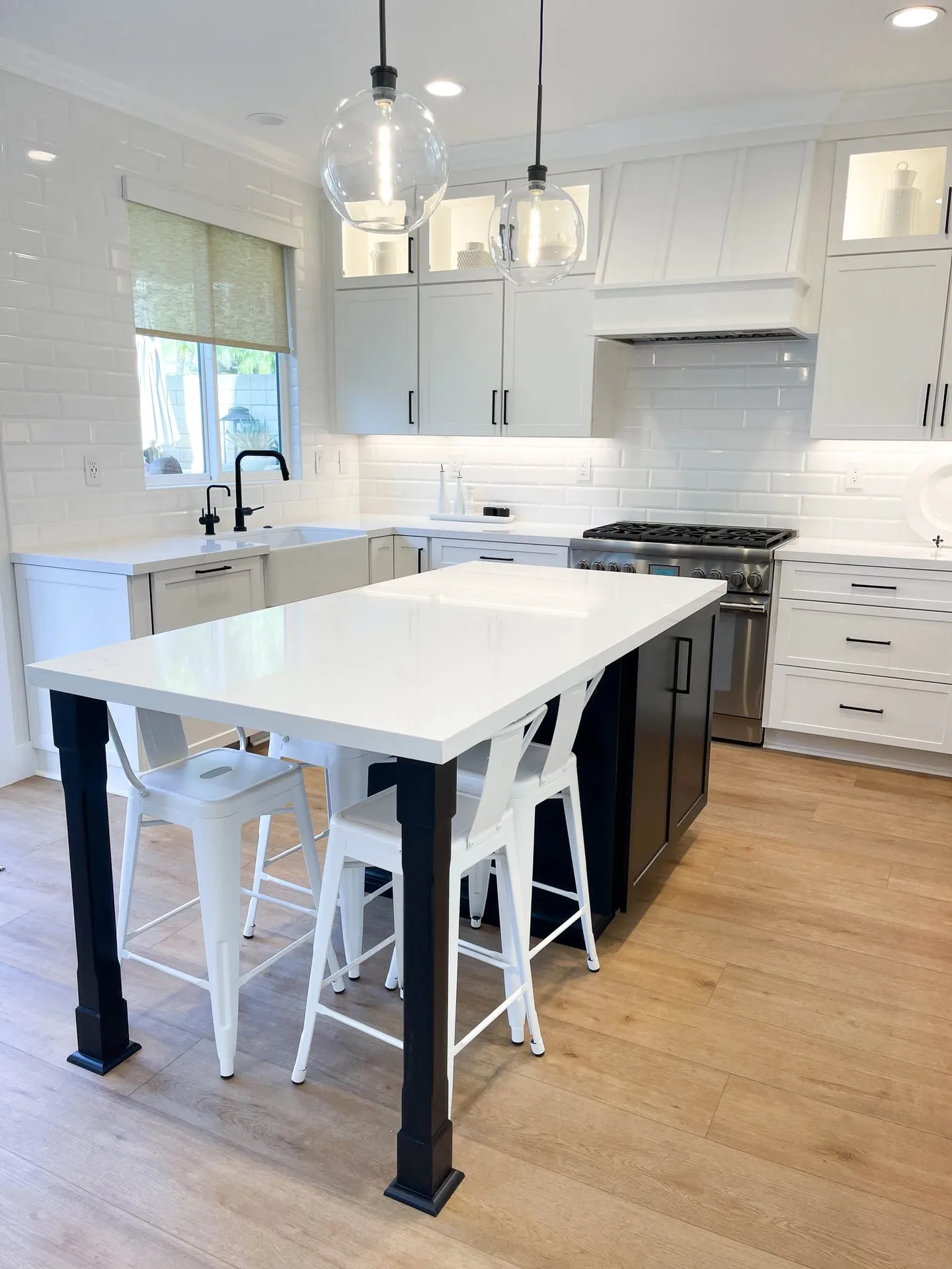 Completed white kitchen with island and pendant lights by Travis Scott Construction