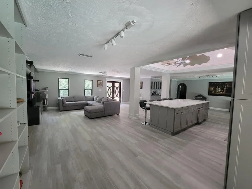 Open living room and kitchen with coordinated gray flooring and cabinetry